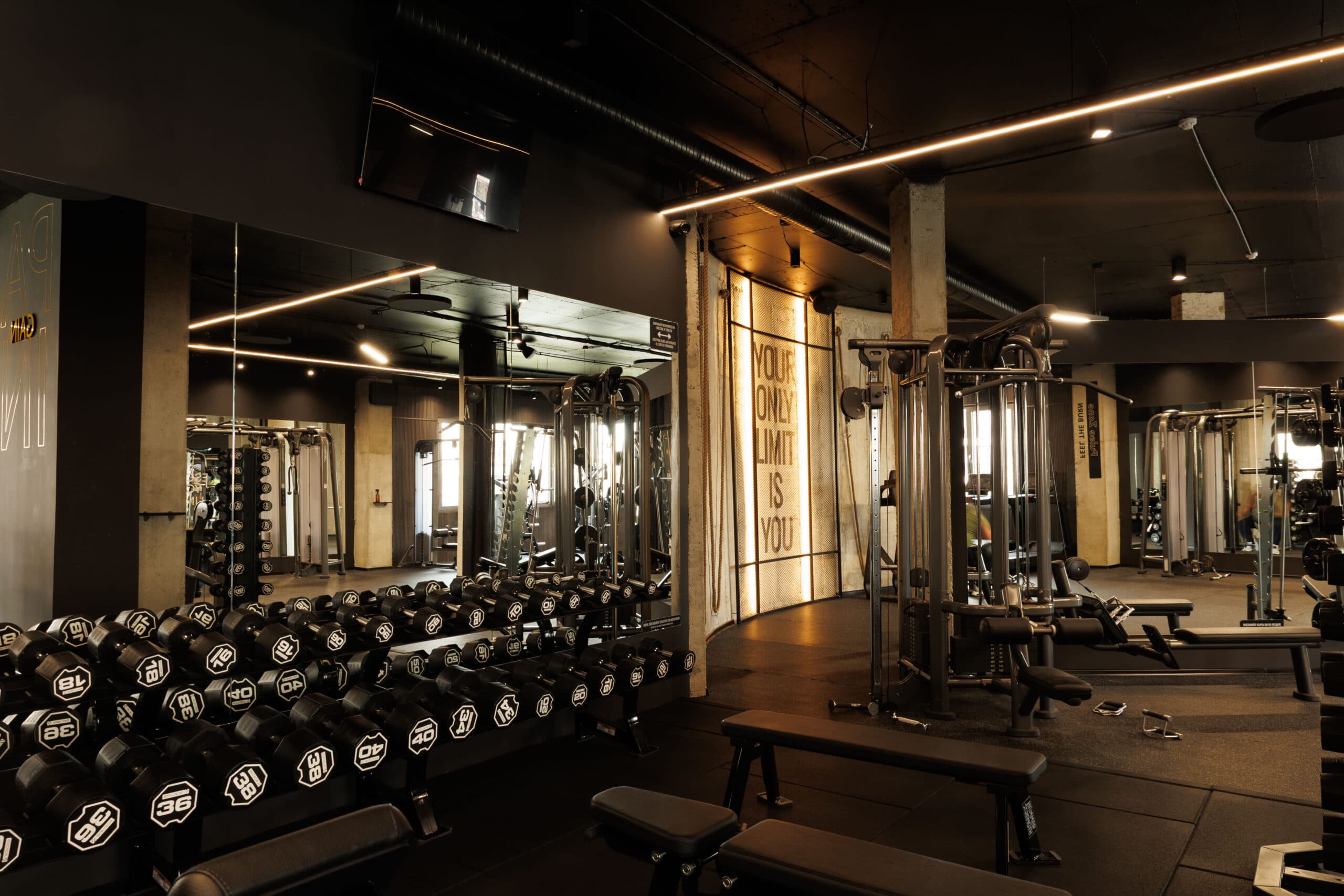 Free-weights area with dumbbells, benches and mirrored walls